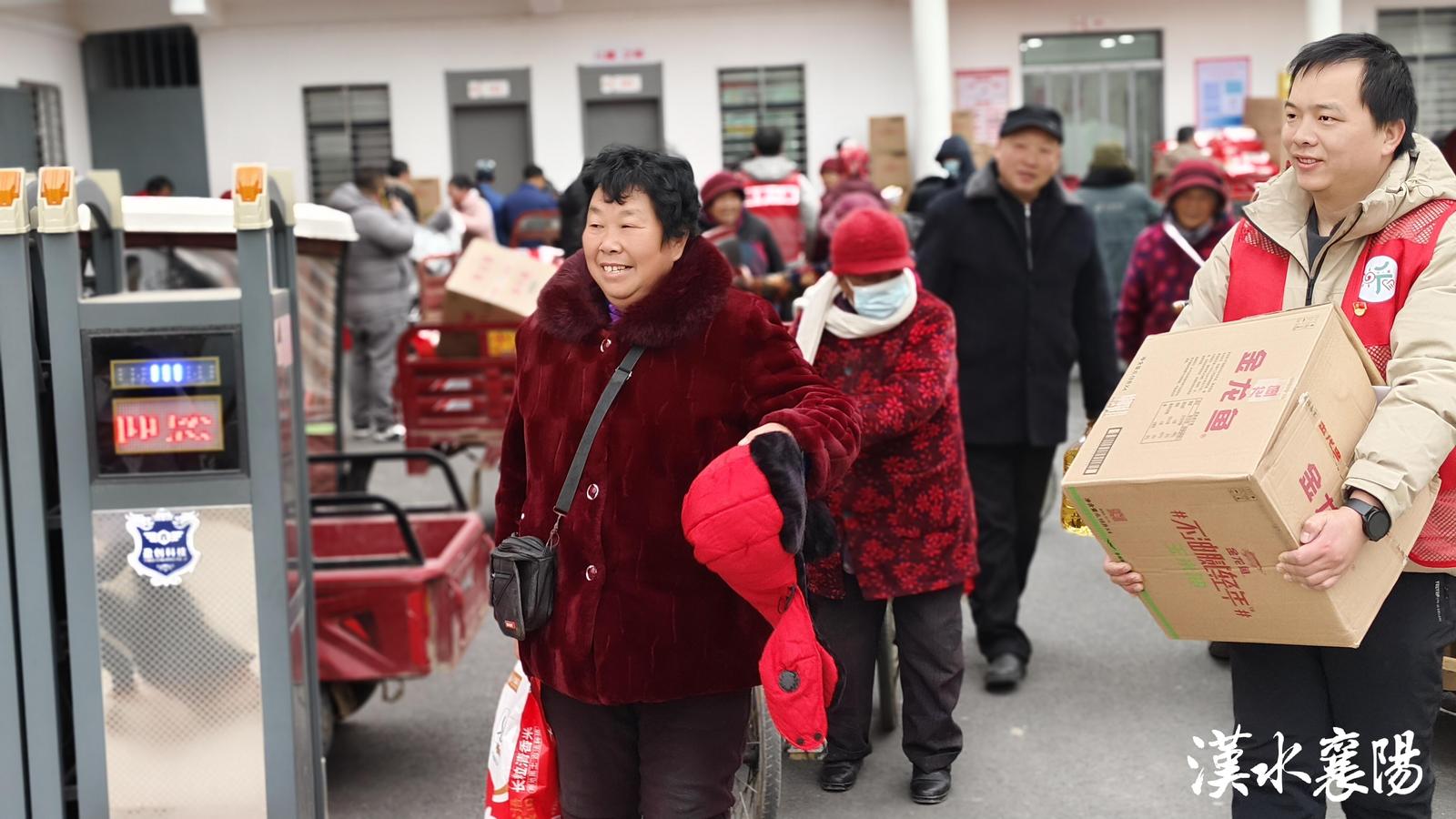 ▲志愿者帮助老年人将福利物品拿到三轮车上